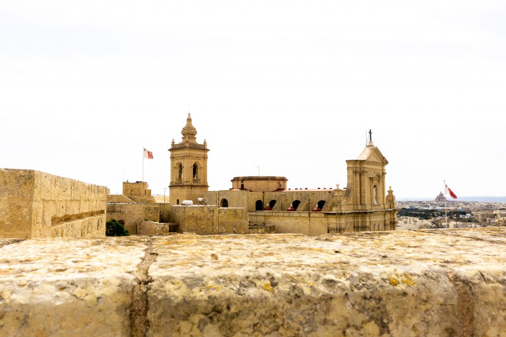 Tan building with two spires and two flags