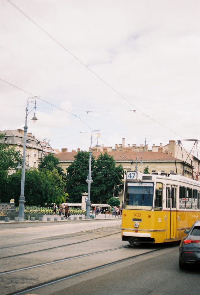 Yellow and white tram numbered '47' on a street in Budapest