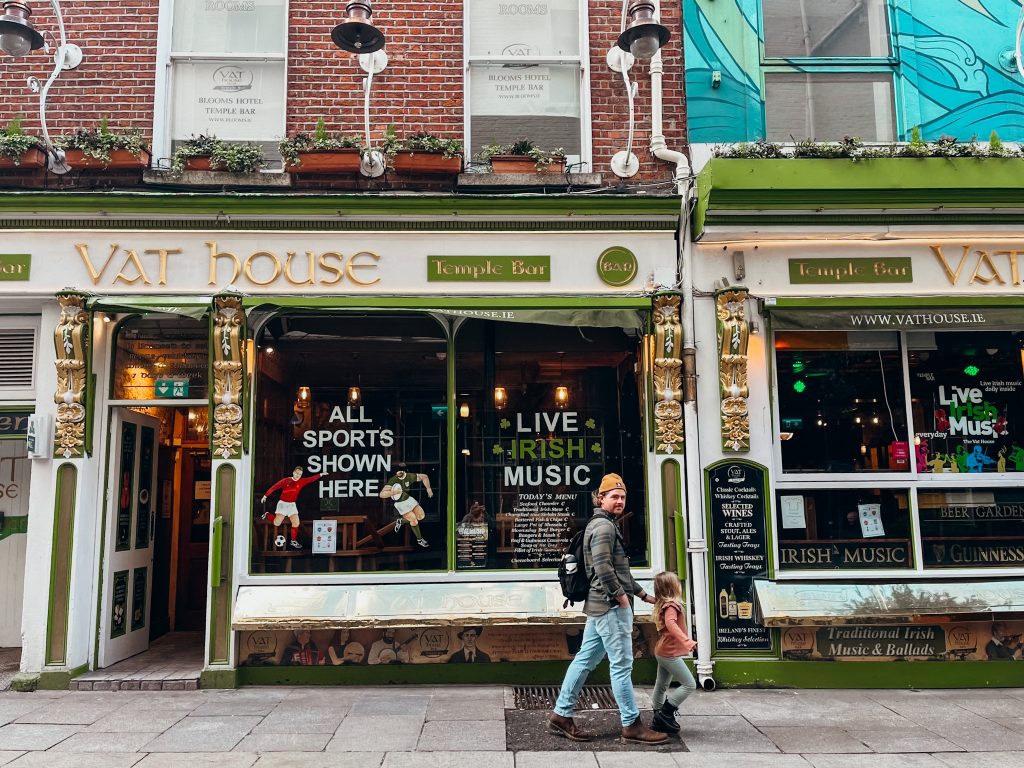 Father and child walk past colorful white, gold and green pub in Dublin Ireland