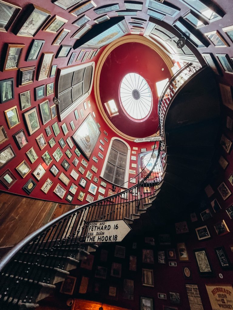Large spiral stairway next to wall covered in red paint and vintage pictures
