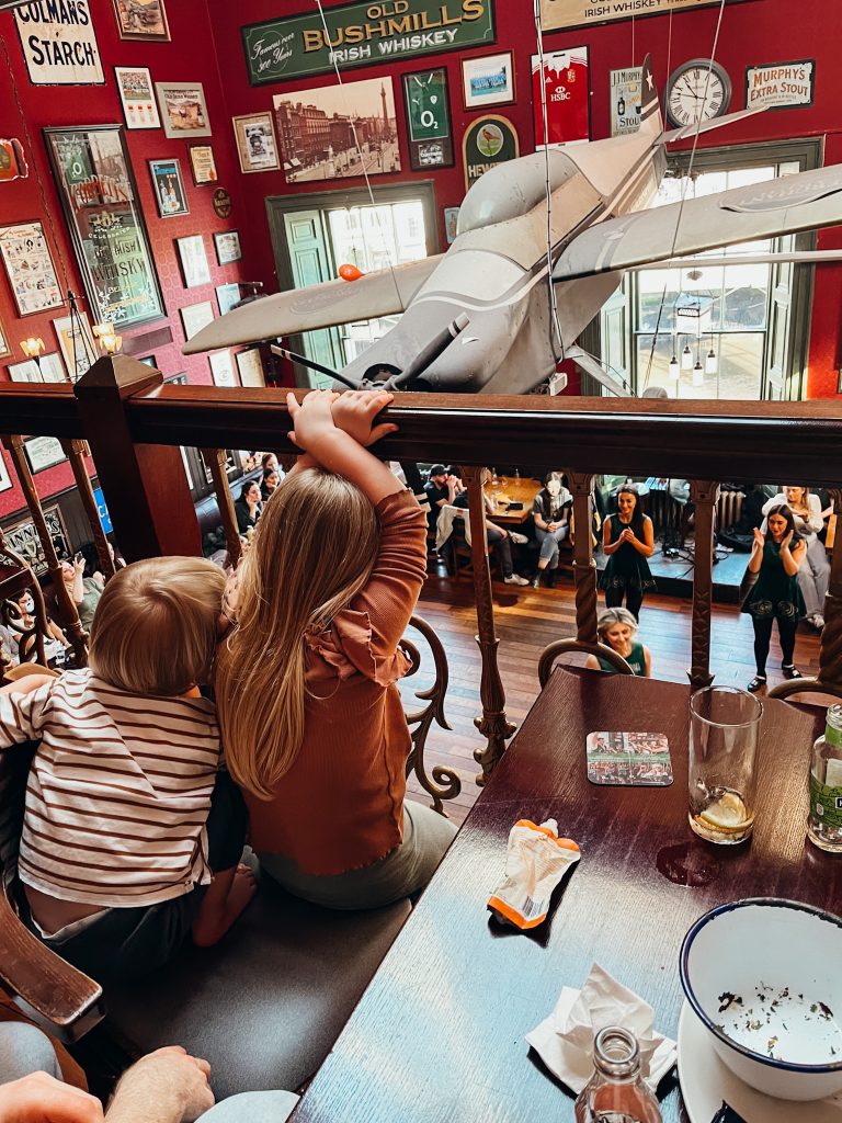 Two children sit at a table overlooking dancing on a wooden dance flor