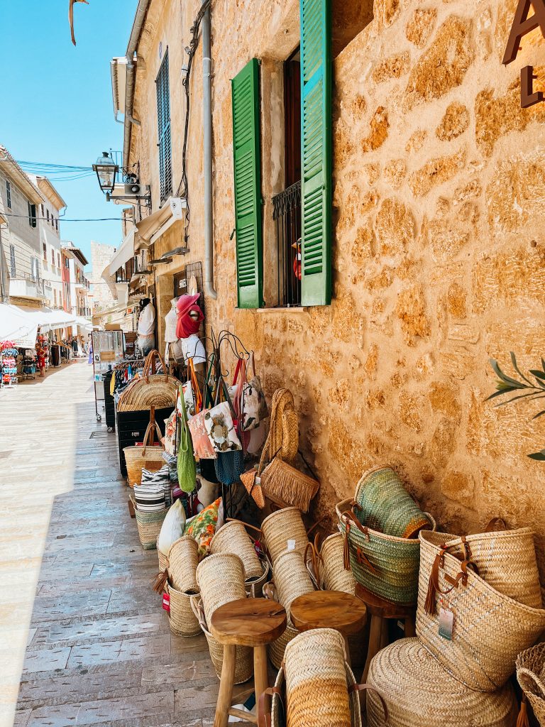 Piles of woven baskets line a rock wall in front of a shop in Alcudia Old Town