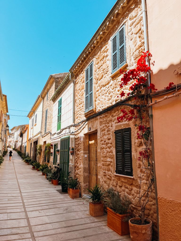 Colorful homes line a small road connected to each other and lined with potted plants