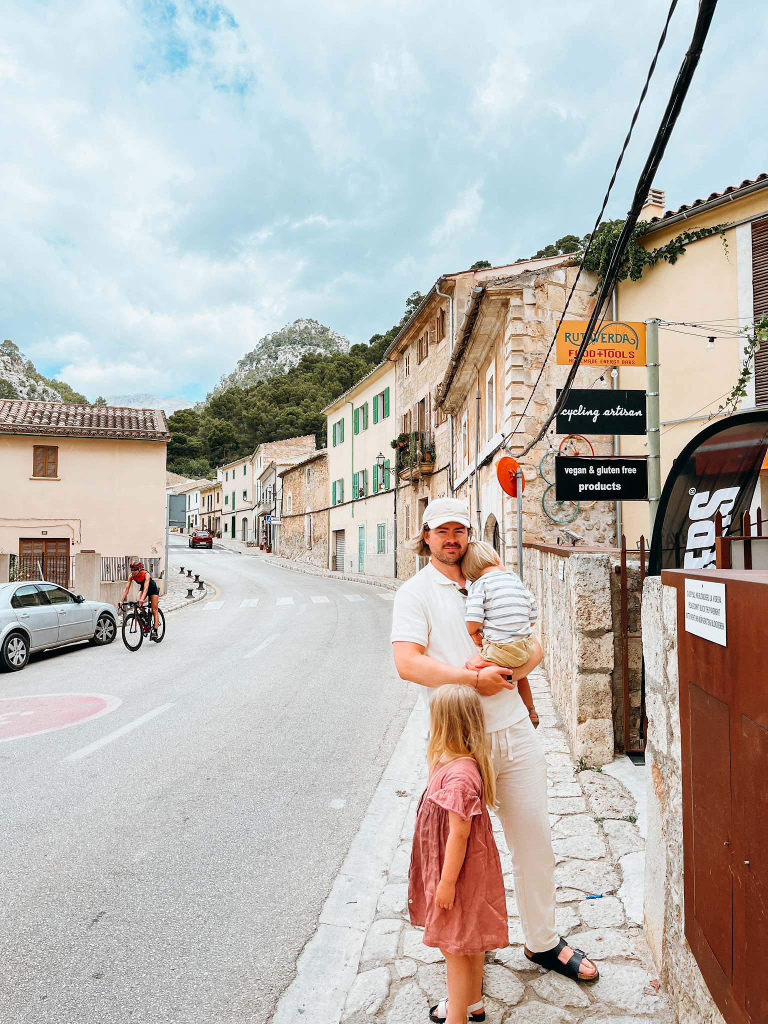 Father and two children stand on sidewalk in old village in Spain
