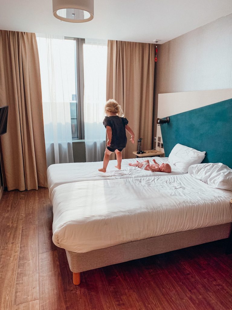 Two children jump on white bed