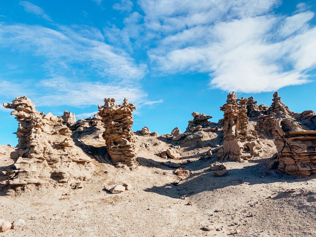 Dirt trail goes through tall rock spires with unique shapes in the desert