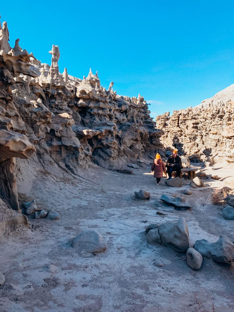 Man and child sit on bench in a valley of tall rock spires