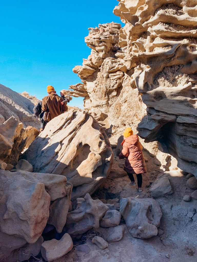Father and child walk on dirt path though past rock spires with unique shapes