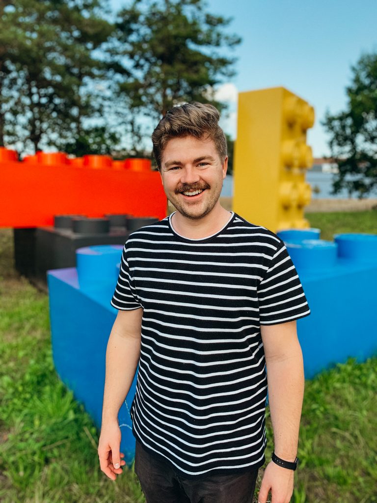 Man stands in front large, colorful LEGO bricks in Billund