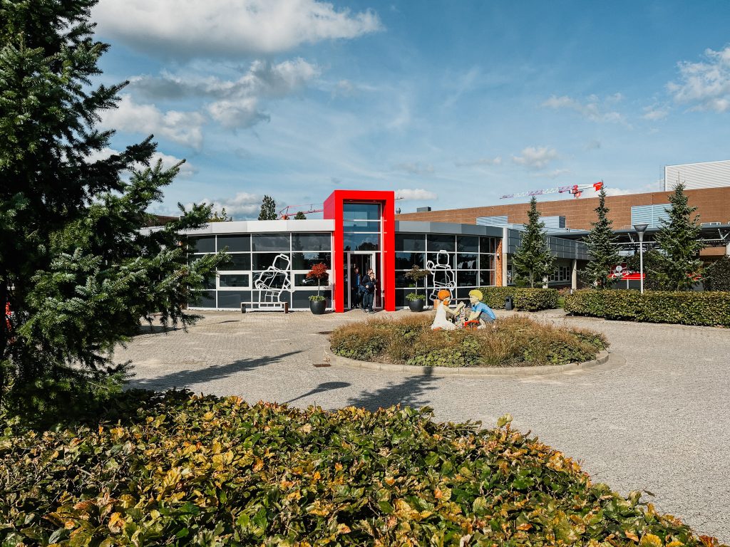 Building with red entrance and large, white minifigure stickers on the windows