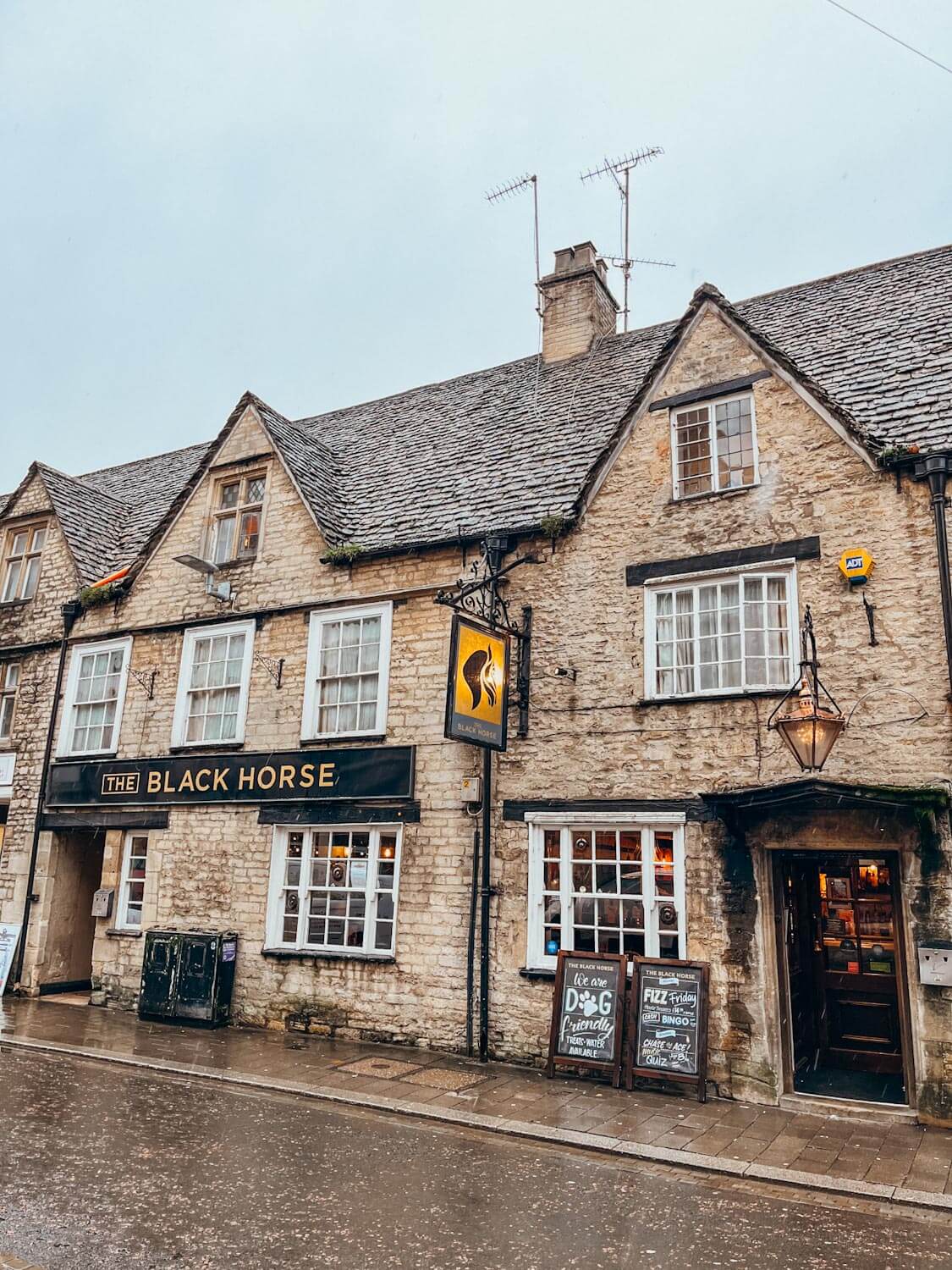 Old brick building on a day trip in the Cotswolds with black sign that reads 'The Black Horse'