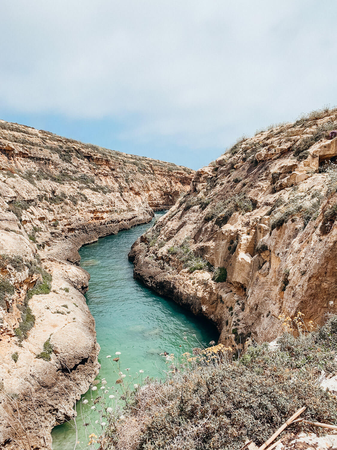 Green water winds it's way past rocky cliffs at Wied Il-Ghasri in Gozo