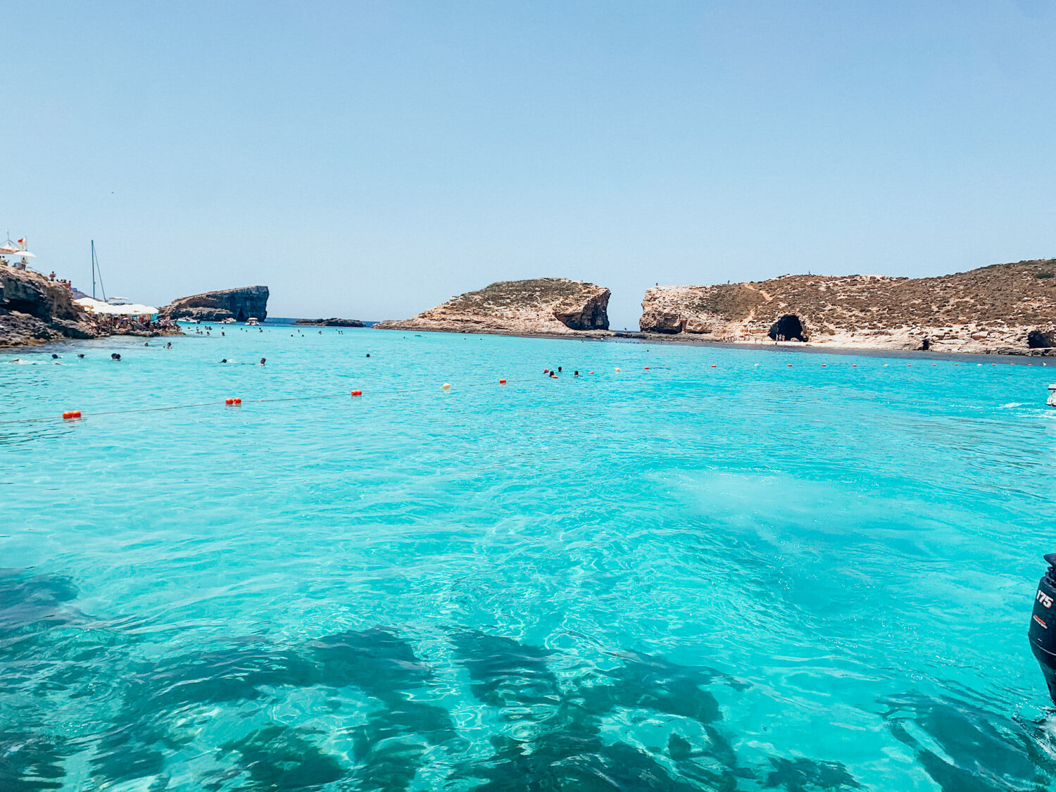 Bright blue water with white boats and a rocky island in the distance