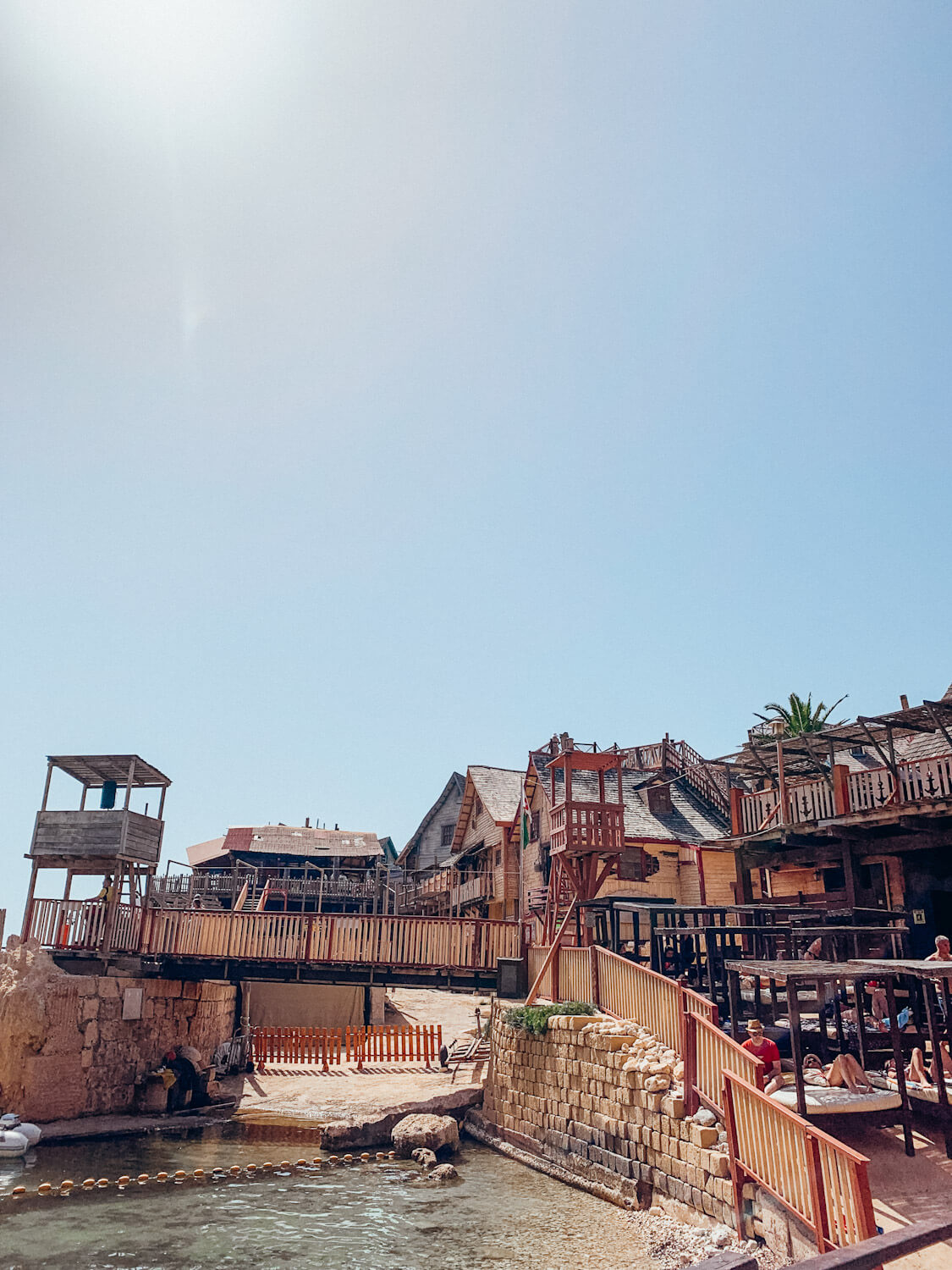 Wooden buildings and railings line the water at Popeye Village