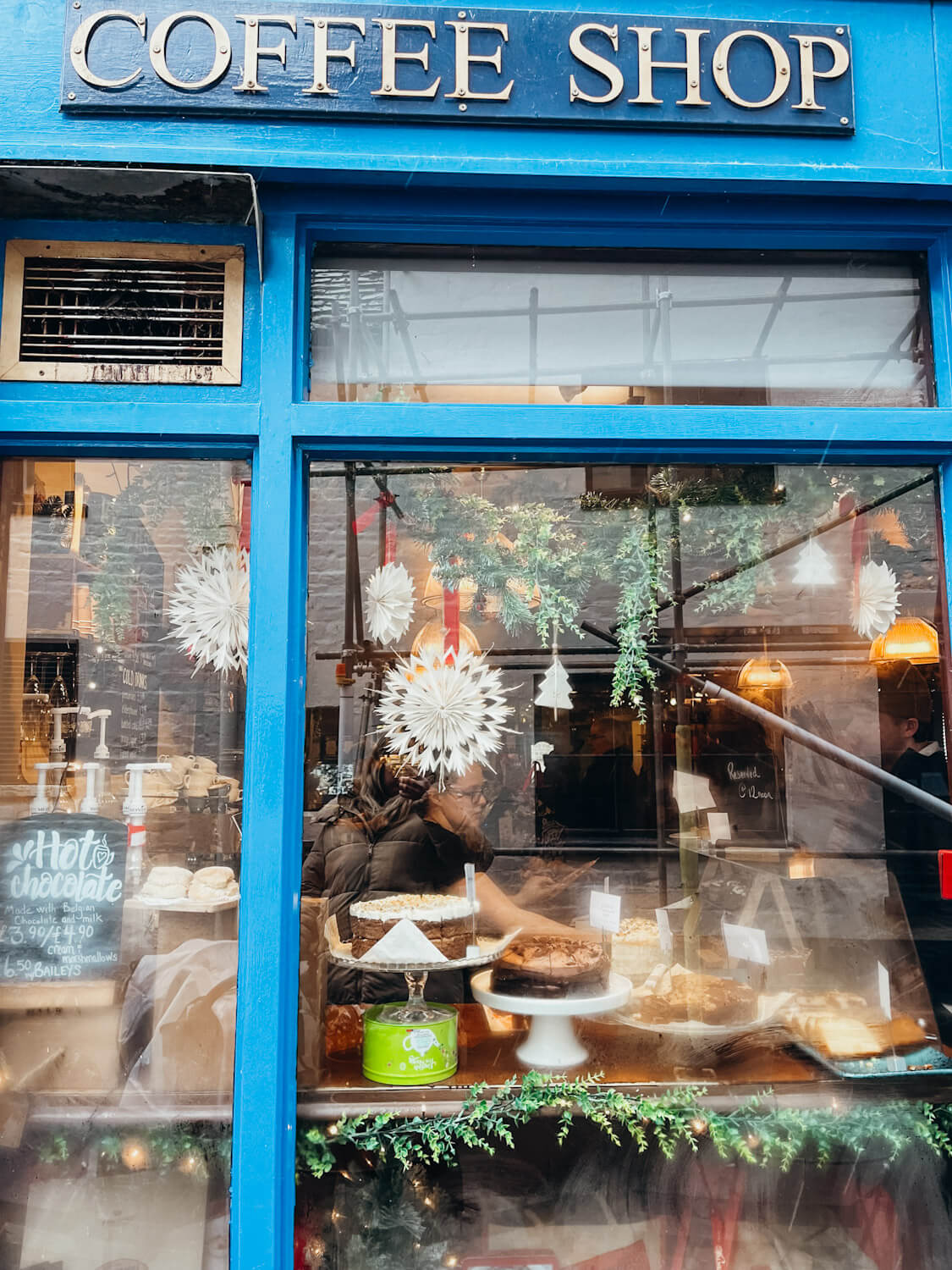 Store window with blue trim and Christmas decorations hung