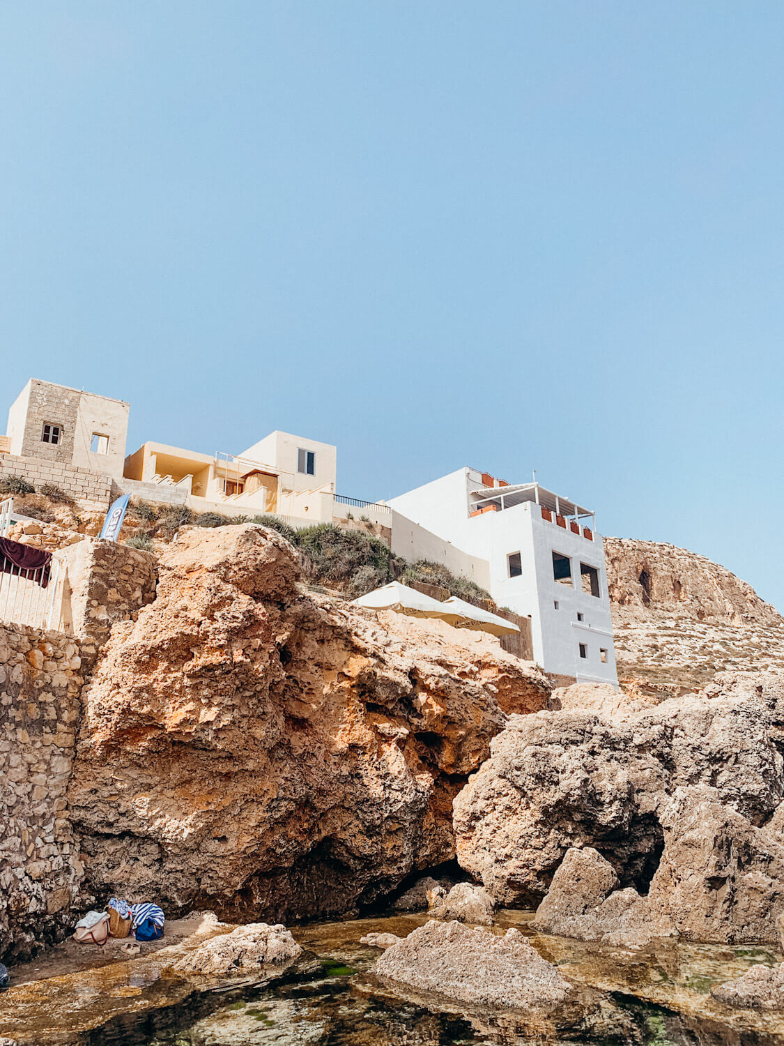 Large white building built atop rocky cliff at Ghar Lapsi in Malta