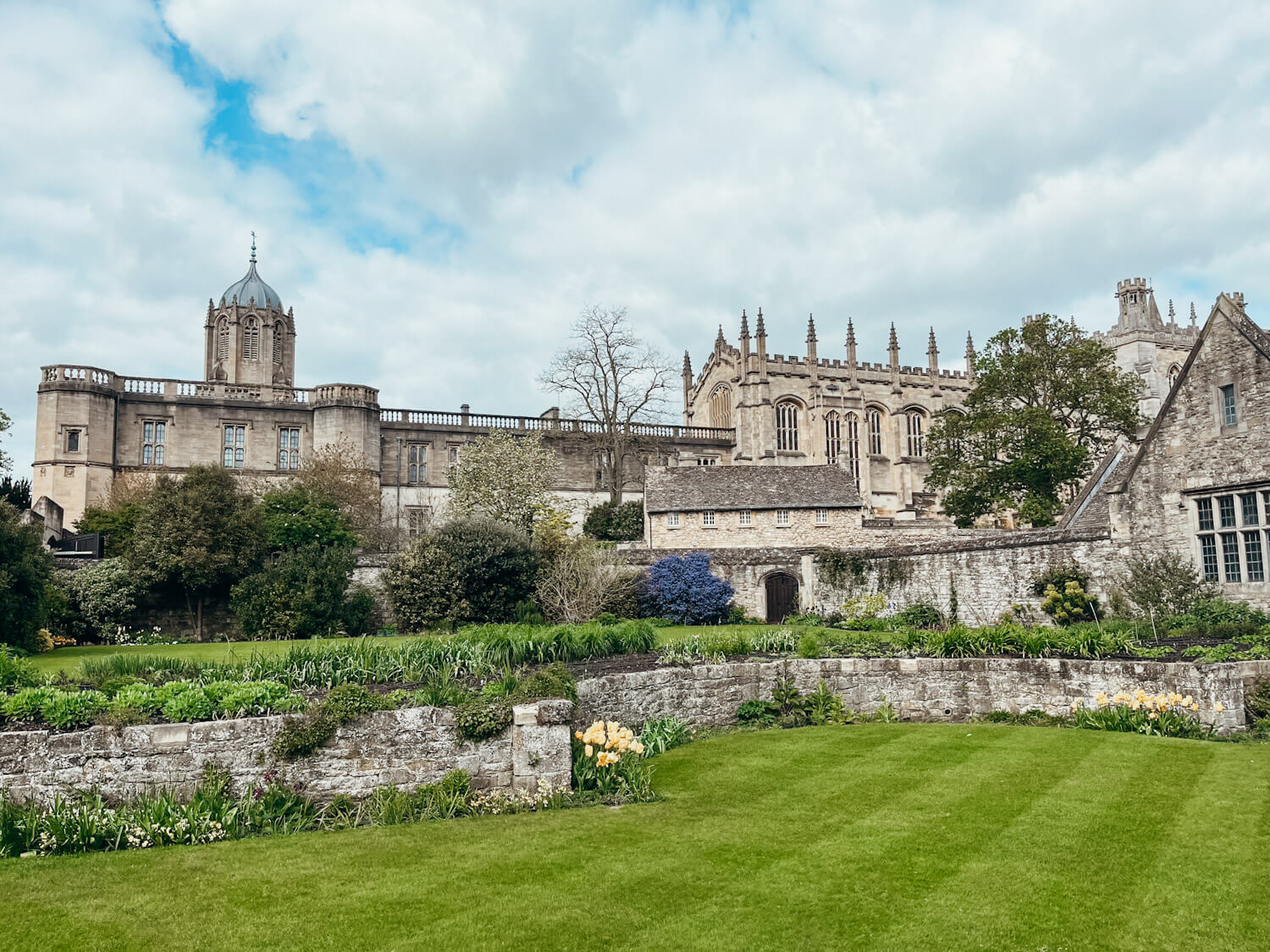 Green grass leads up to old stone buildings with multiple turrets atop