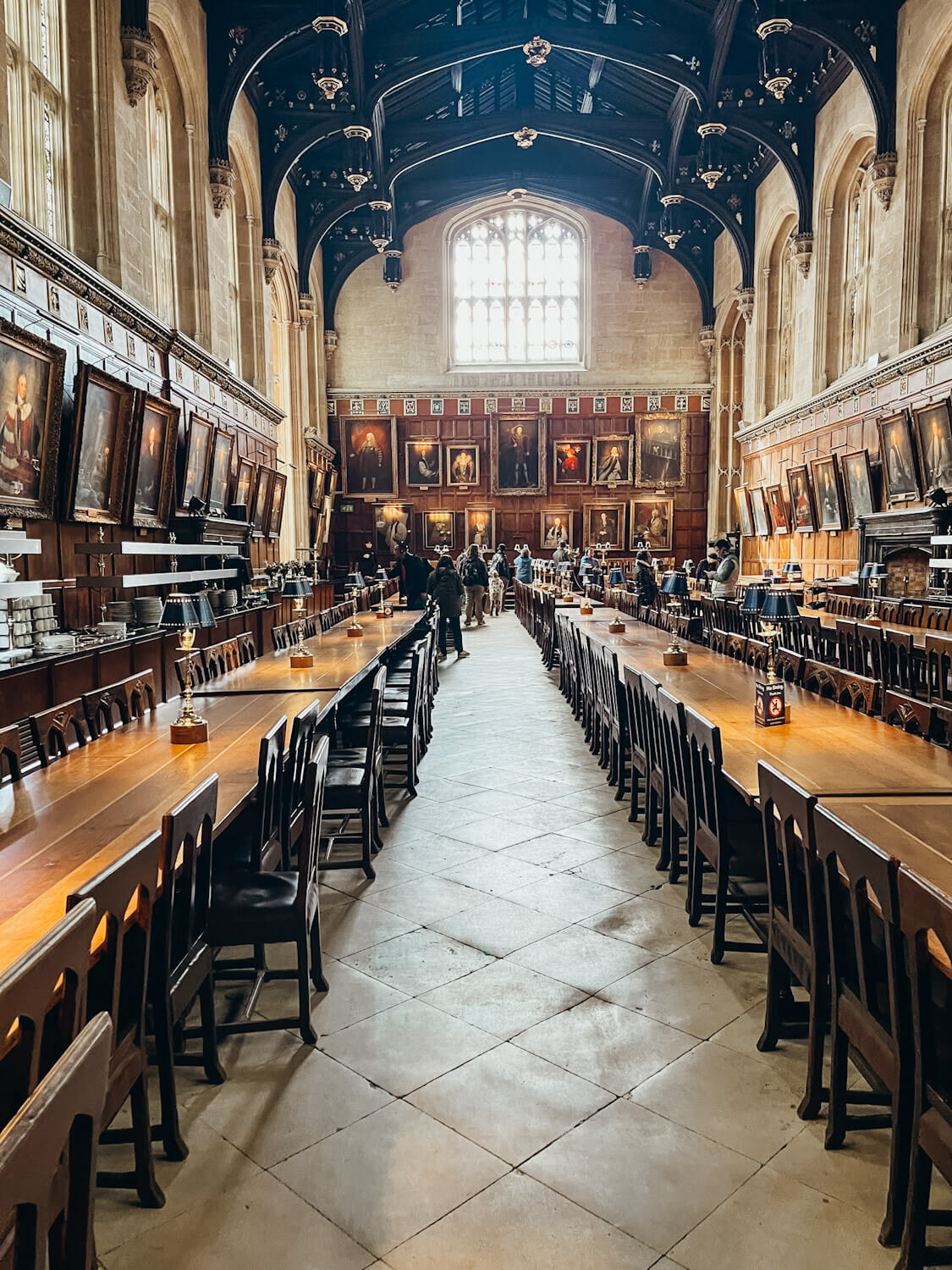 Long wooden banquet tables in grand hall lined with portraits at Christ Church