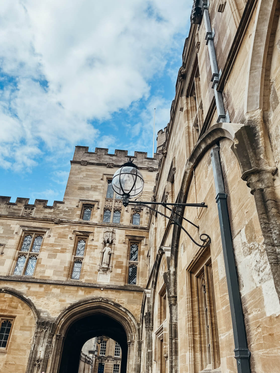 Old honey-colored stone building in Oxford with glass lamp attached to the wall
