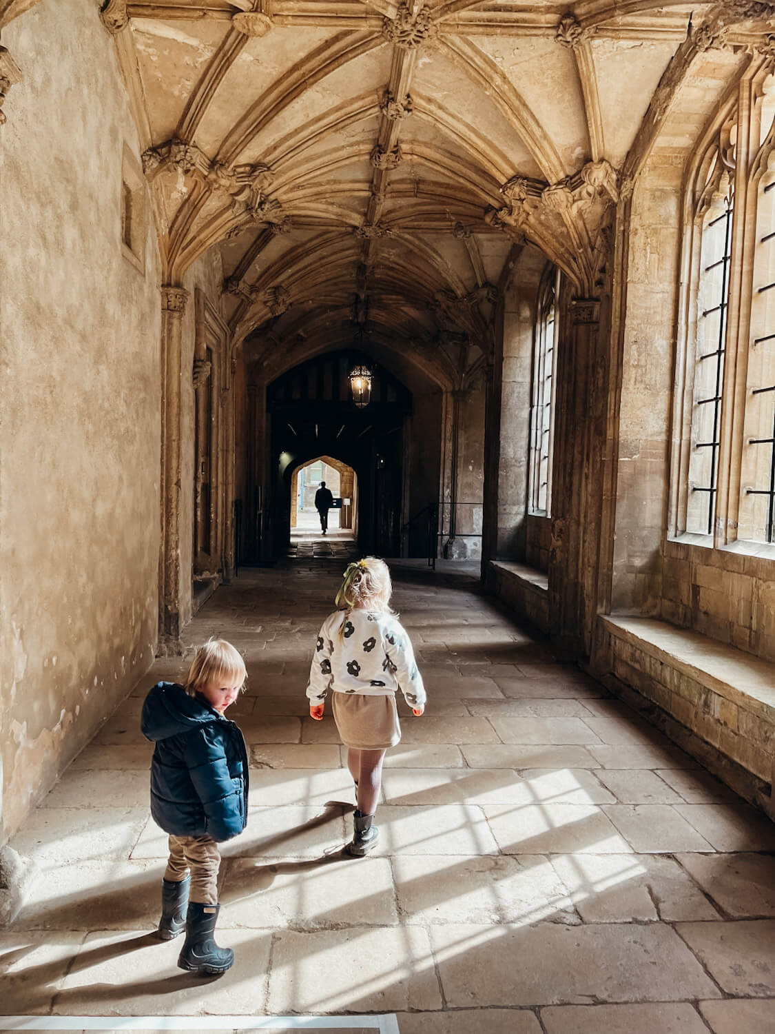 Two children walk down stone hallway at Christ Church College