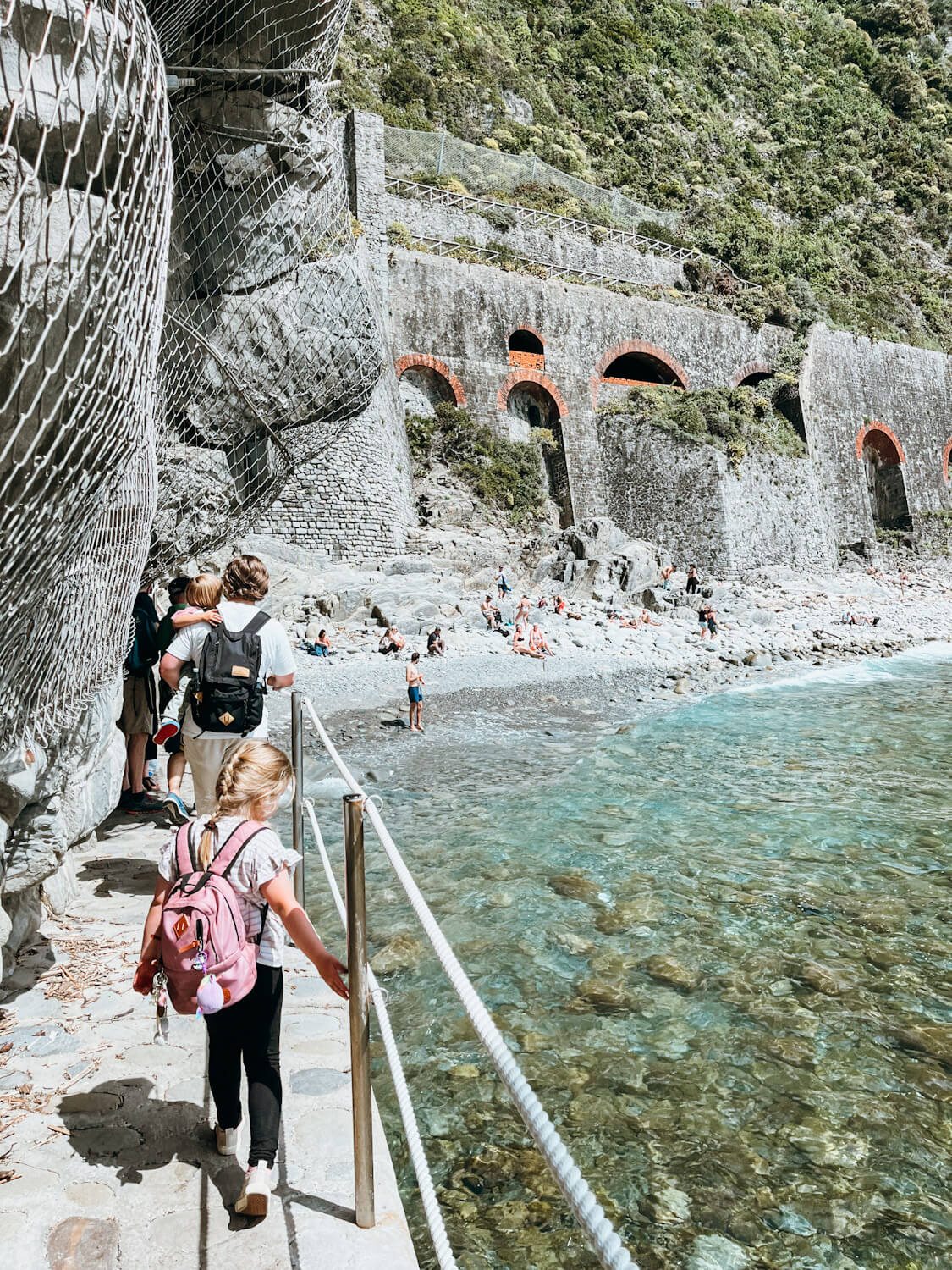 People walk to rocky beach in Riomaggiore