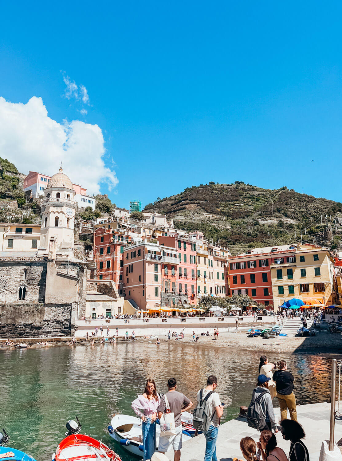 Colorful buildings line a small beach in the Vernazza harbor