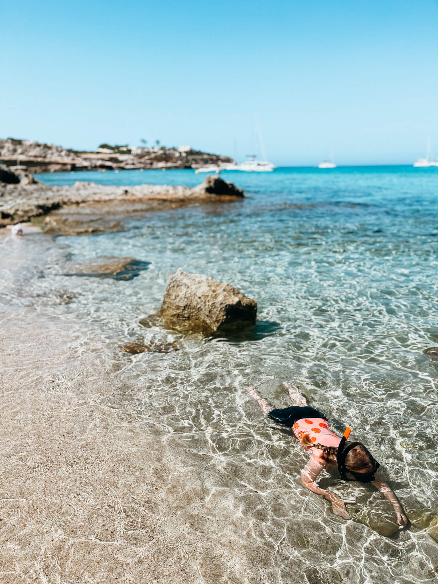 Child snorkels in blue clear water in Ibiza Spain