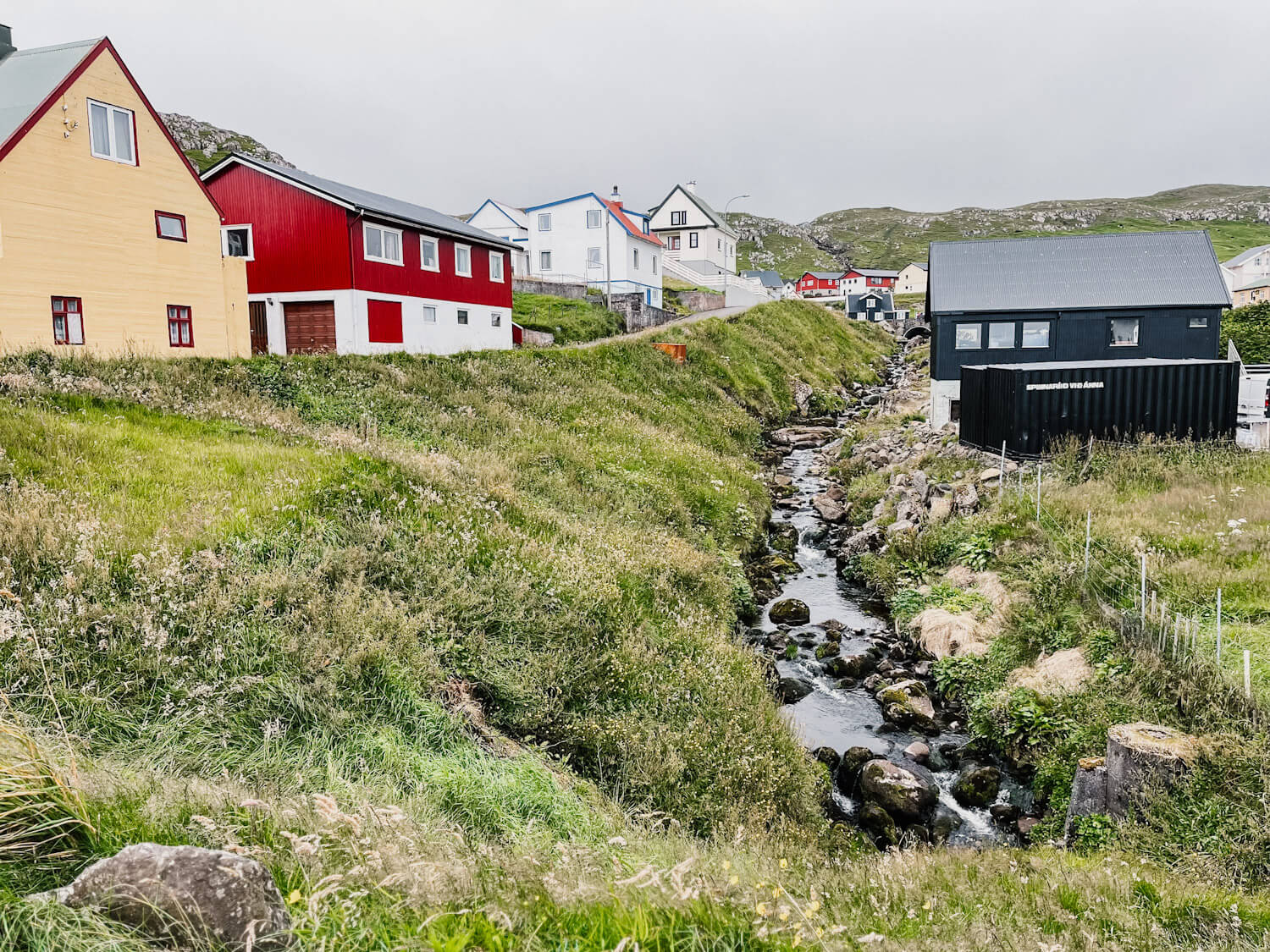 Colorful buildings next to stream on Sandoy Island in the Faroe Islands