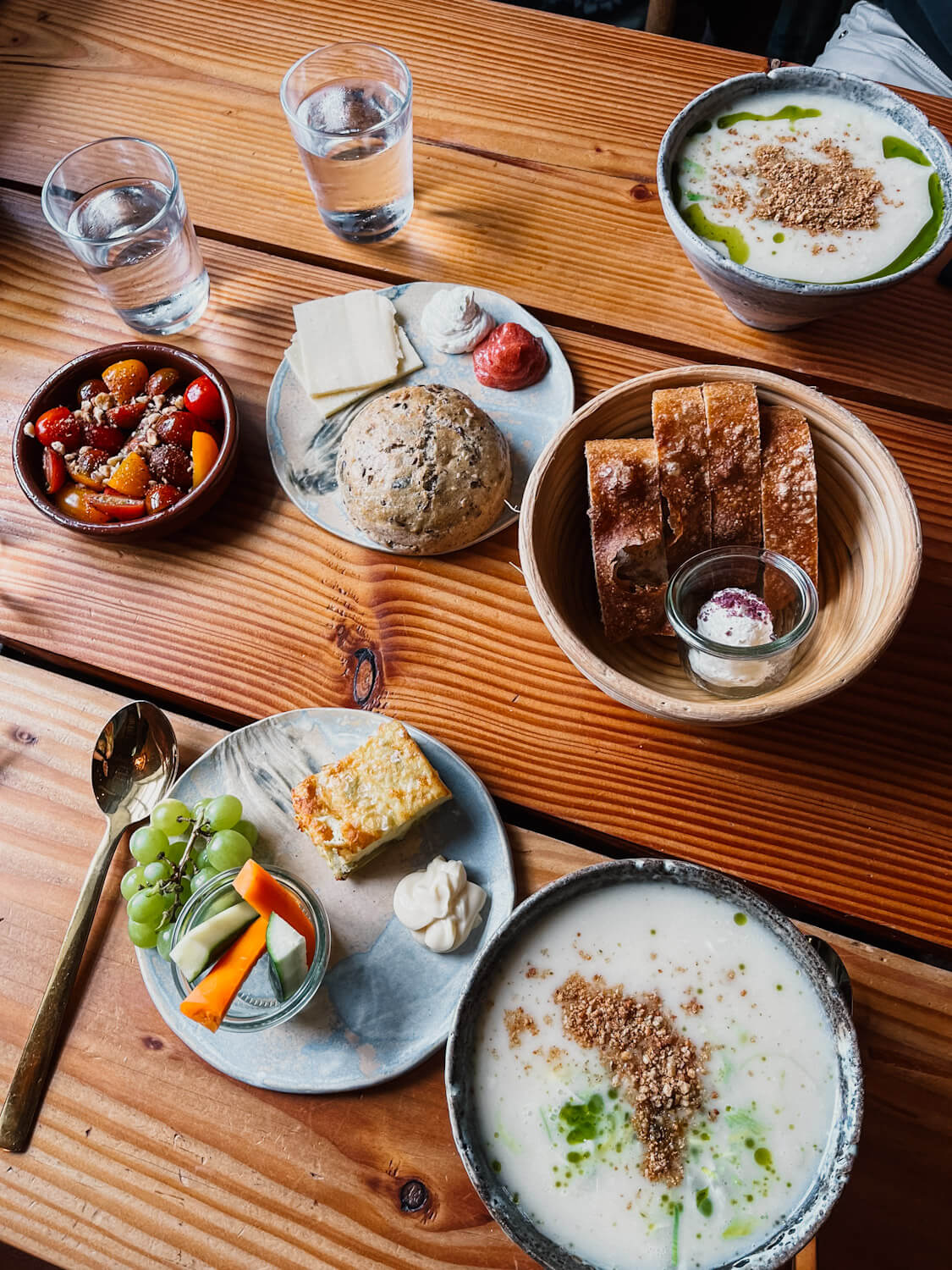 Table with multiple plates of food including soup and bread