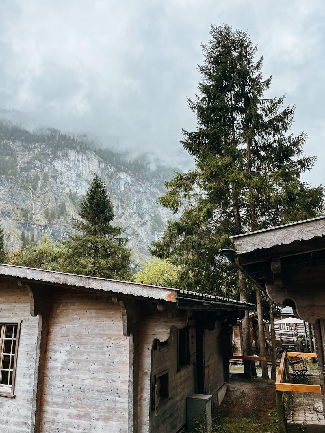 Wooden cottages with pine tree and cloudy mountain views in Lauterbrunnen Switzerland