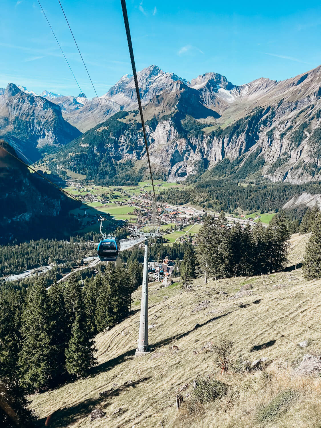 Ariel views form the Oeschinen Lake cable car of the cable car line and surrounding mountains with a village at the bottom