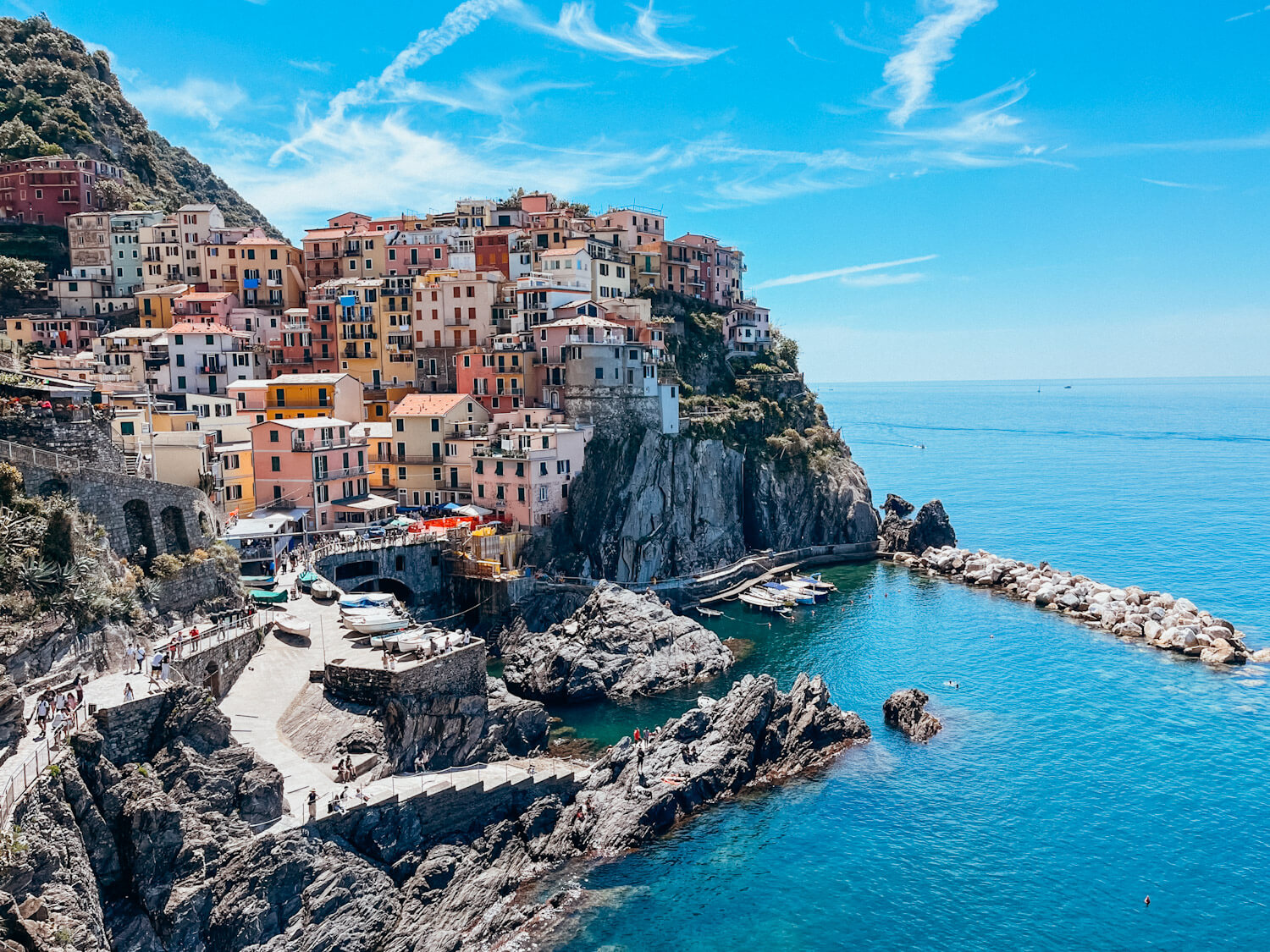 Colorful buildings on a rocky cliff in Manarola surrounding a harbor