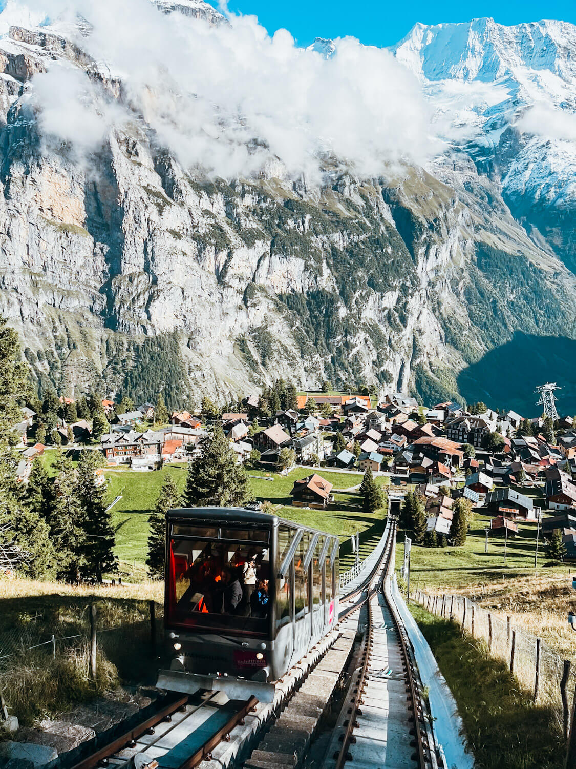 Allmendhubel funicular riding up a track with mountain views behind