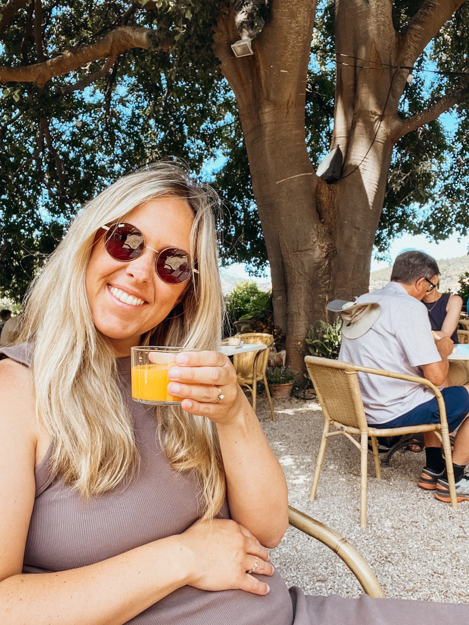 Woman holds a cup of orange juice at ecovinyassa
