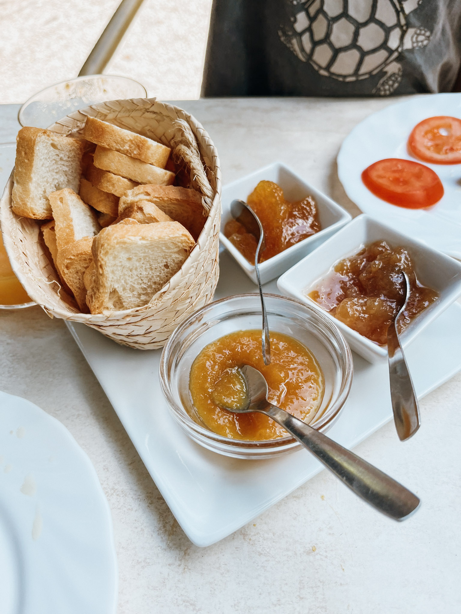 Basket with bread next to glass containers of orange marmalade