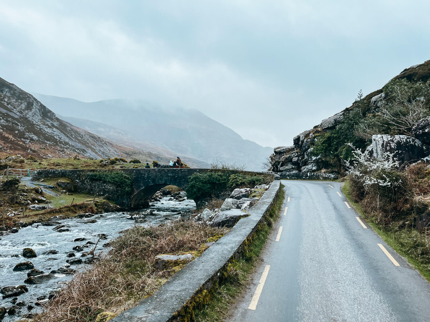 Small road leading to stone arch bridge over river in Gap of Dunloe Killarney Ireland