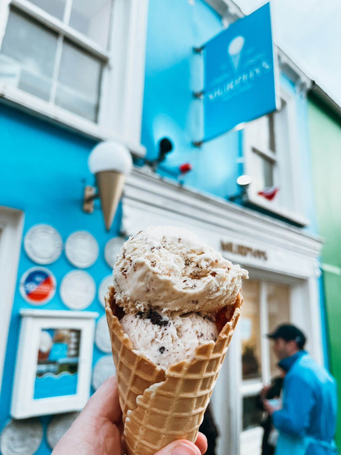 Close up of an ice cream cone in front of a blue and white building in Dingle Ireland