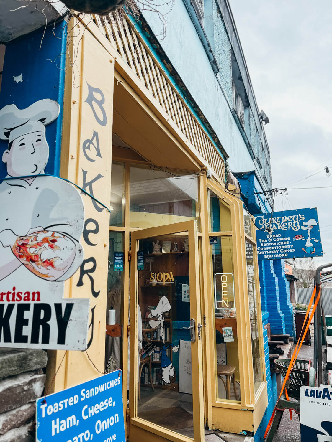 Yellow and blue signs on a building reading 'Courtney's Bakery' in Dingle Town