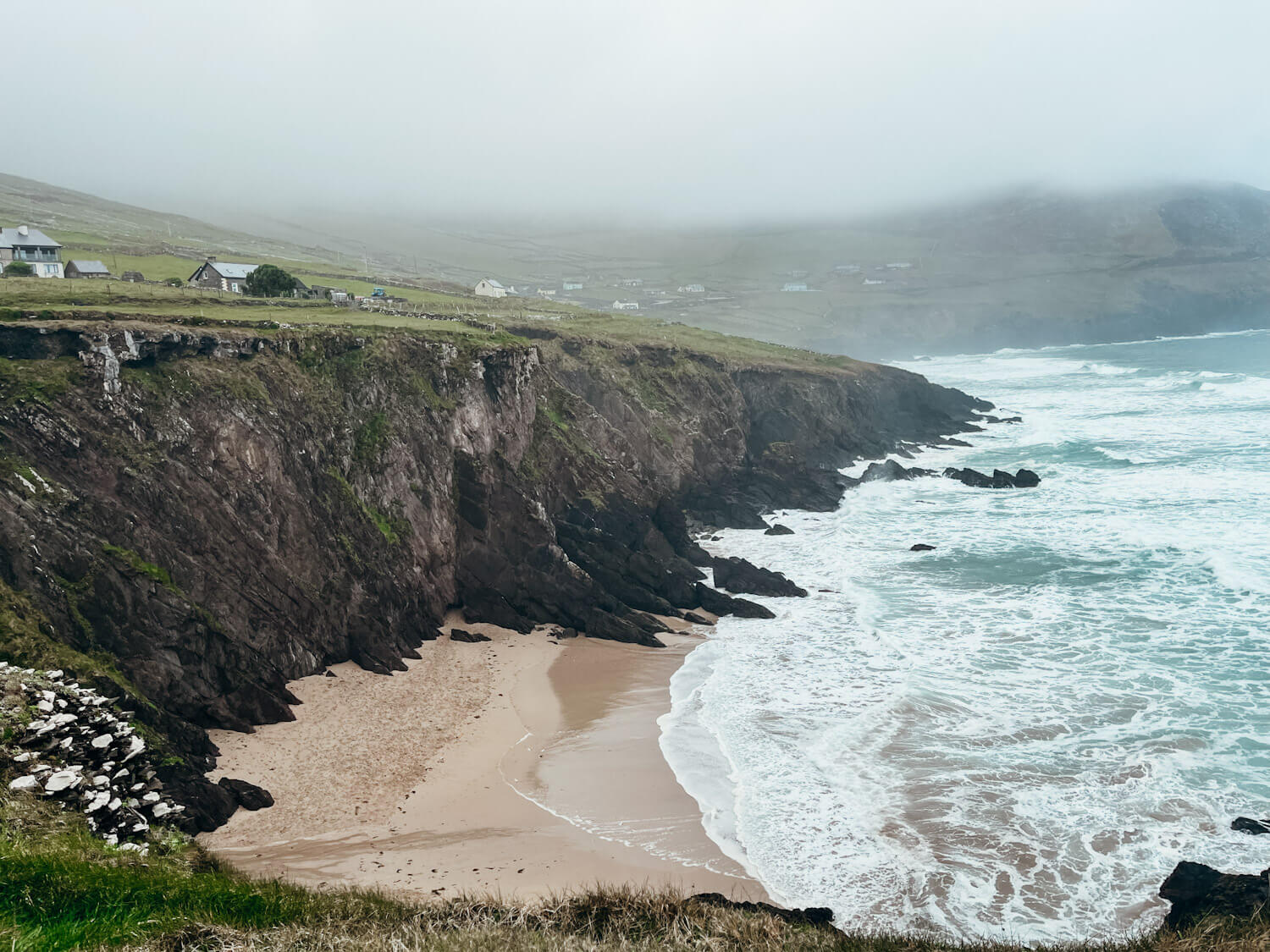 Sandy beach with cliffs in the fog in Dingle Ireland: Coumeenoole Beach
