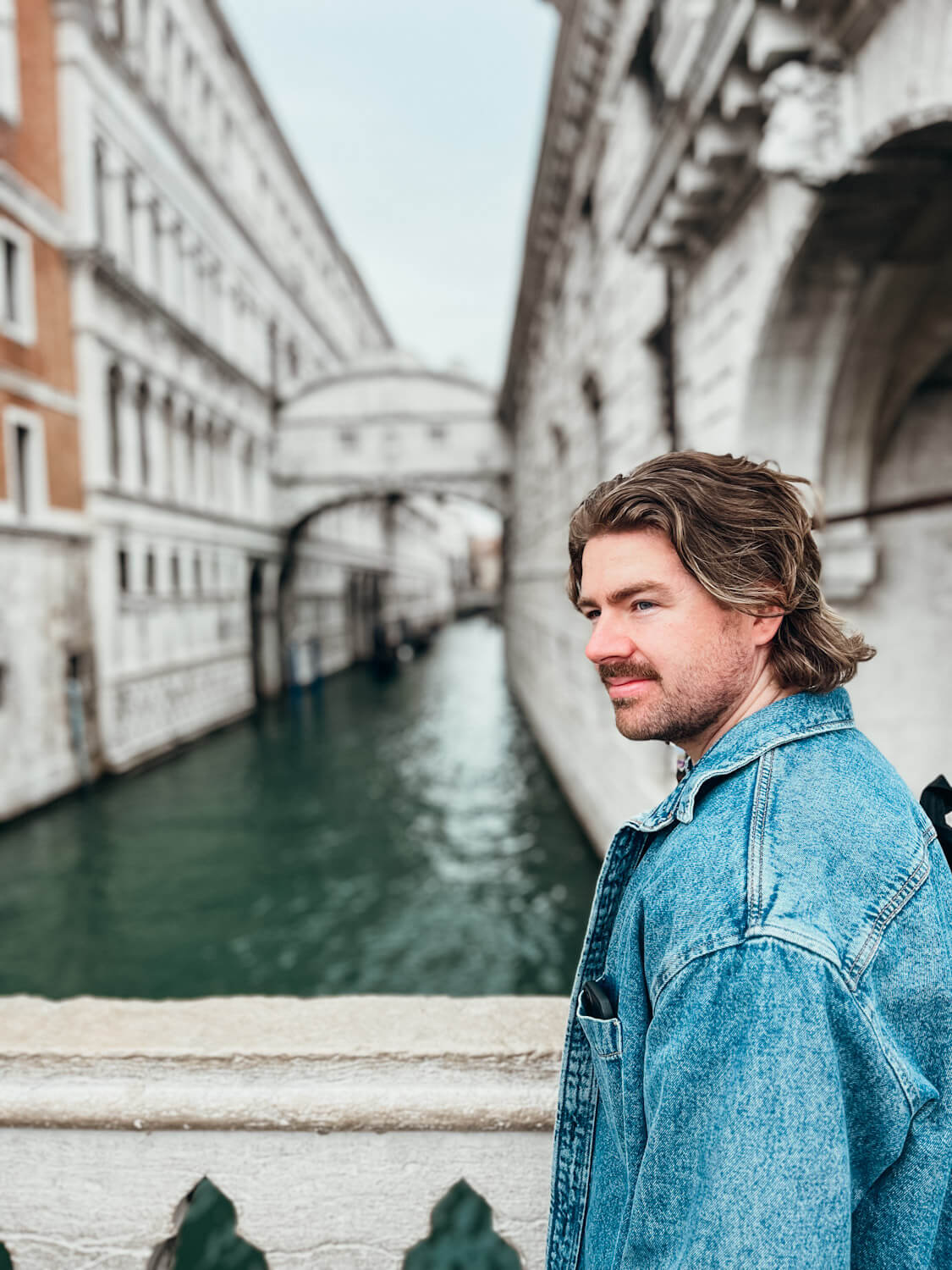 Close up of man with white stone bridge in the background in Venice in May