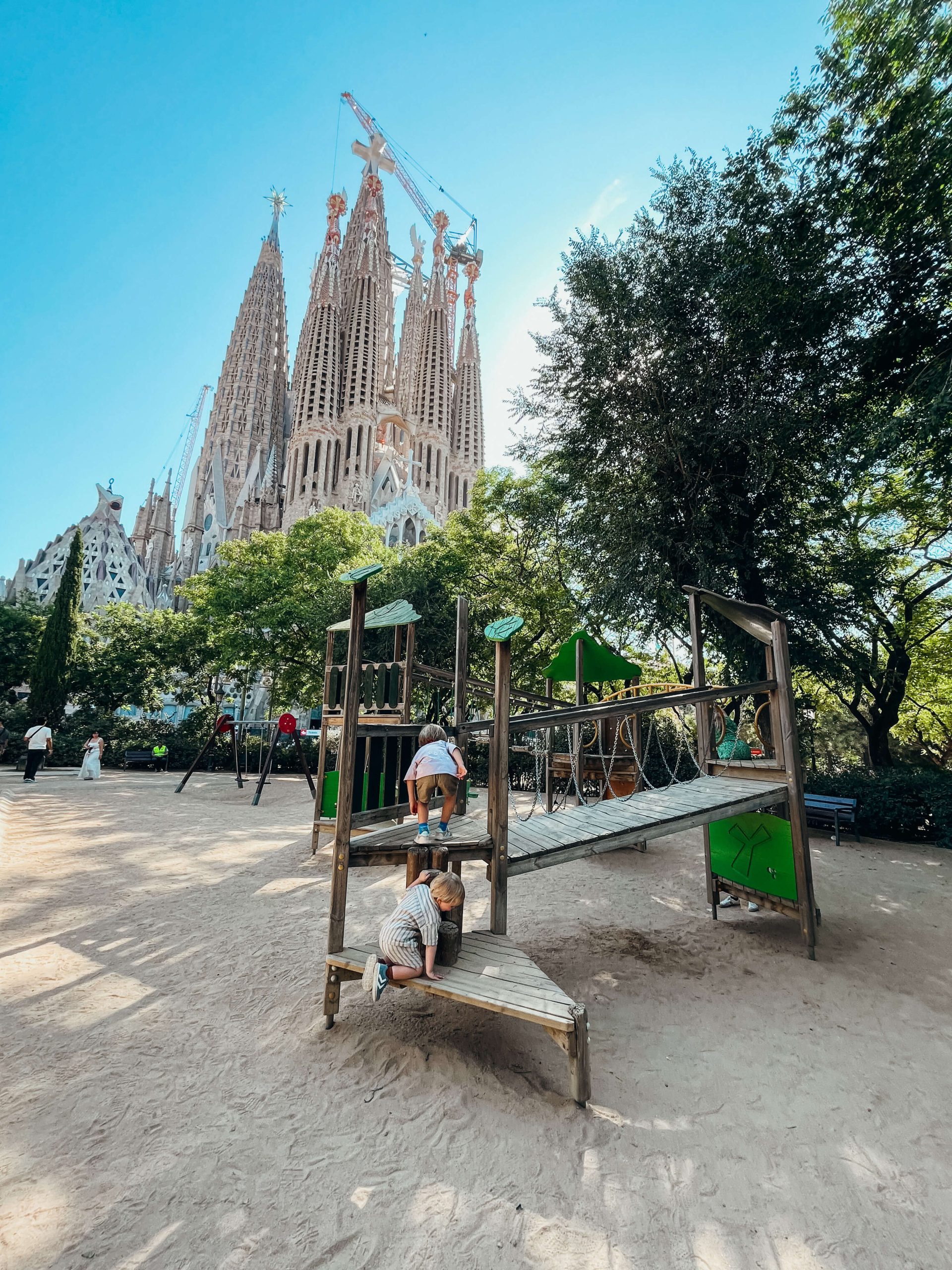 Kids climb on wooden playground in front of Sagrada Familia in Barcelona with kids