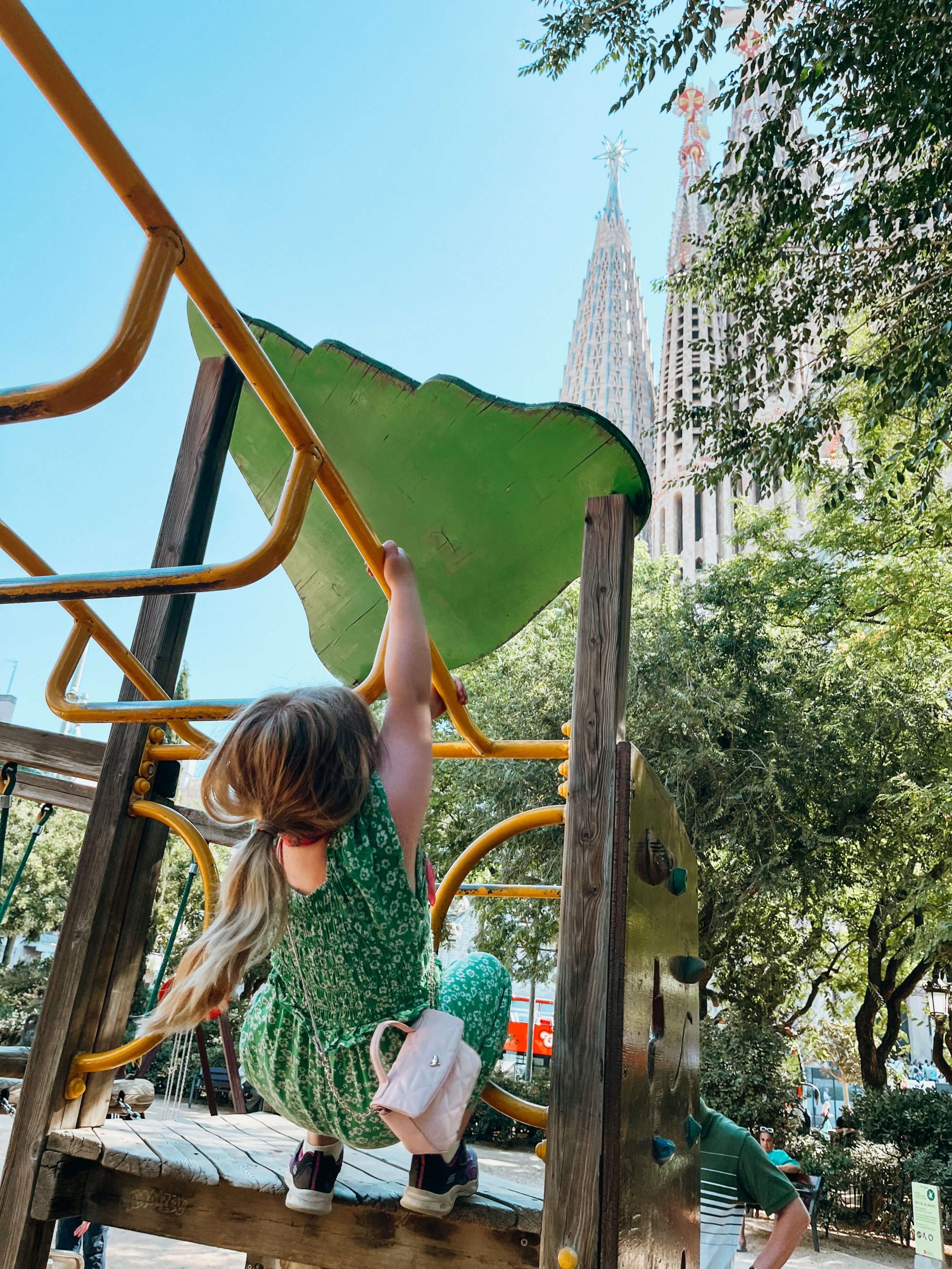Girl climbs on monkey bars at playground next to Sagrada Famalia in Barcelona