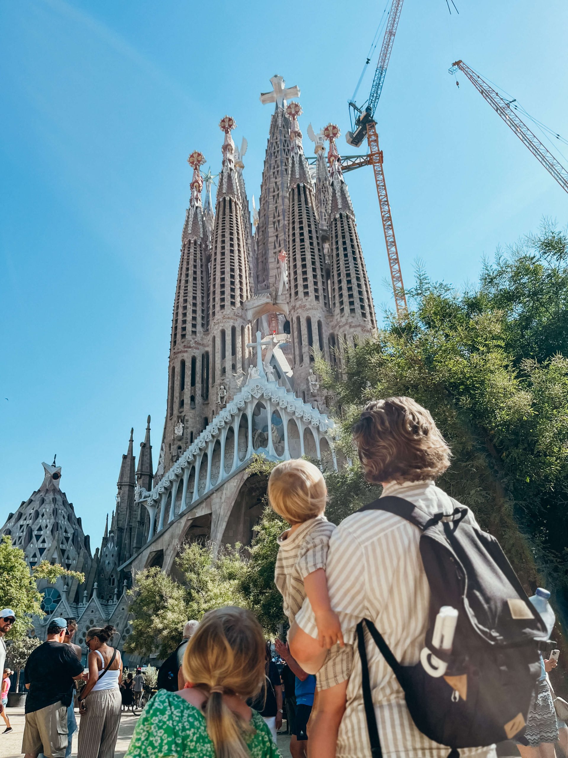 Dad and young children stand looking up at Sagrada Familia as a family in Barcelona Spain