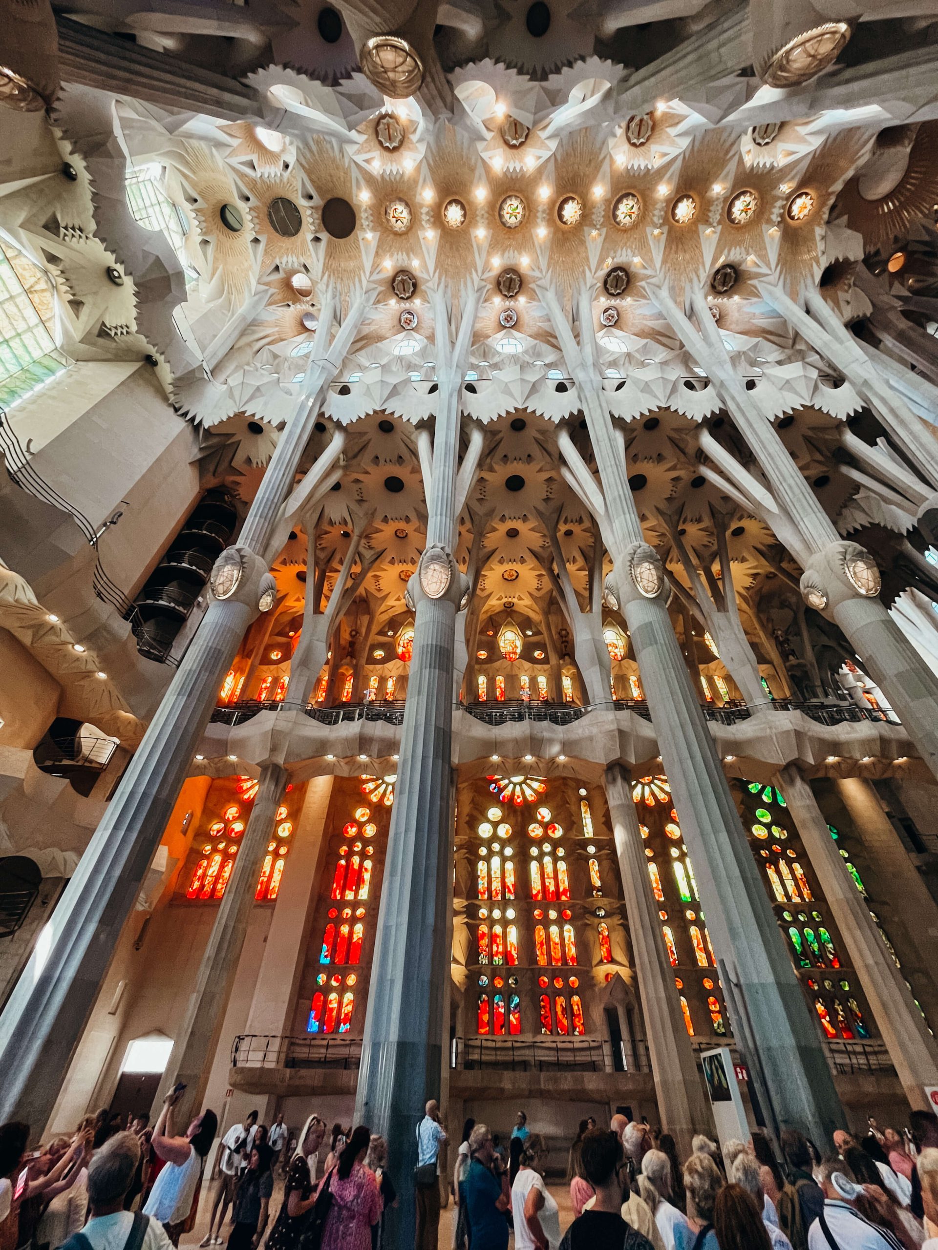 Inside view of Sagrada Familia with large stone pillars and colorful stained glass