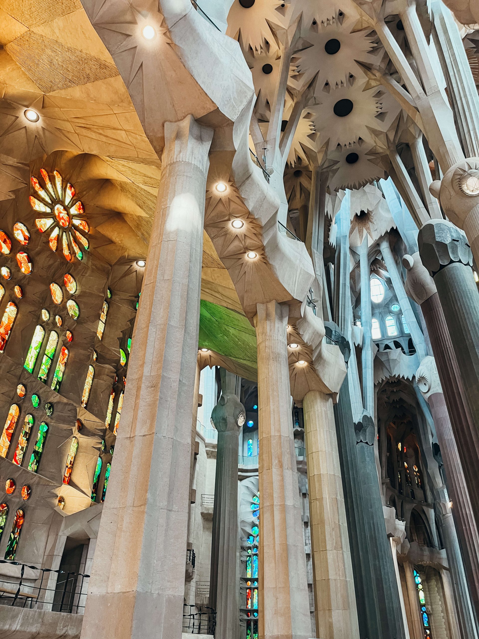 Inside view of Sagrada Familia with large stone pillars and colorful stained glass