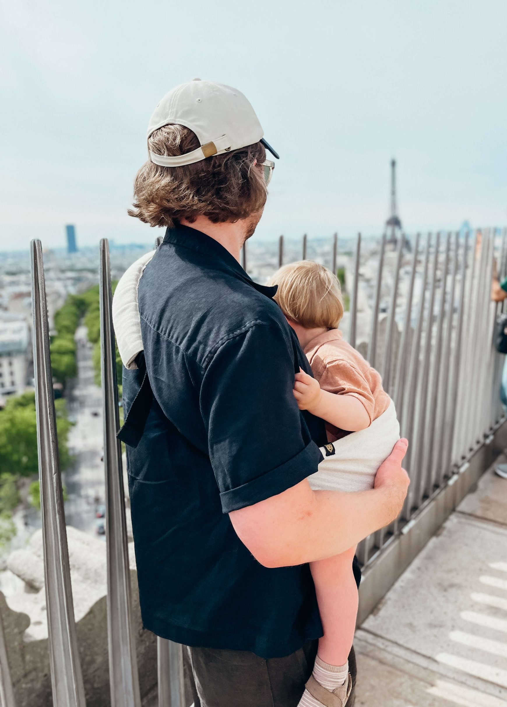 Father holds toddler in his arms atop the Arc de Triomphe in Paris in May