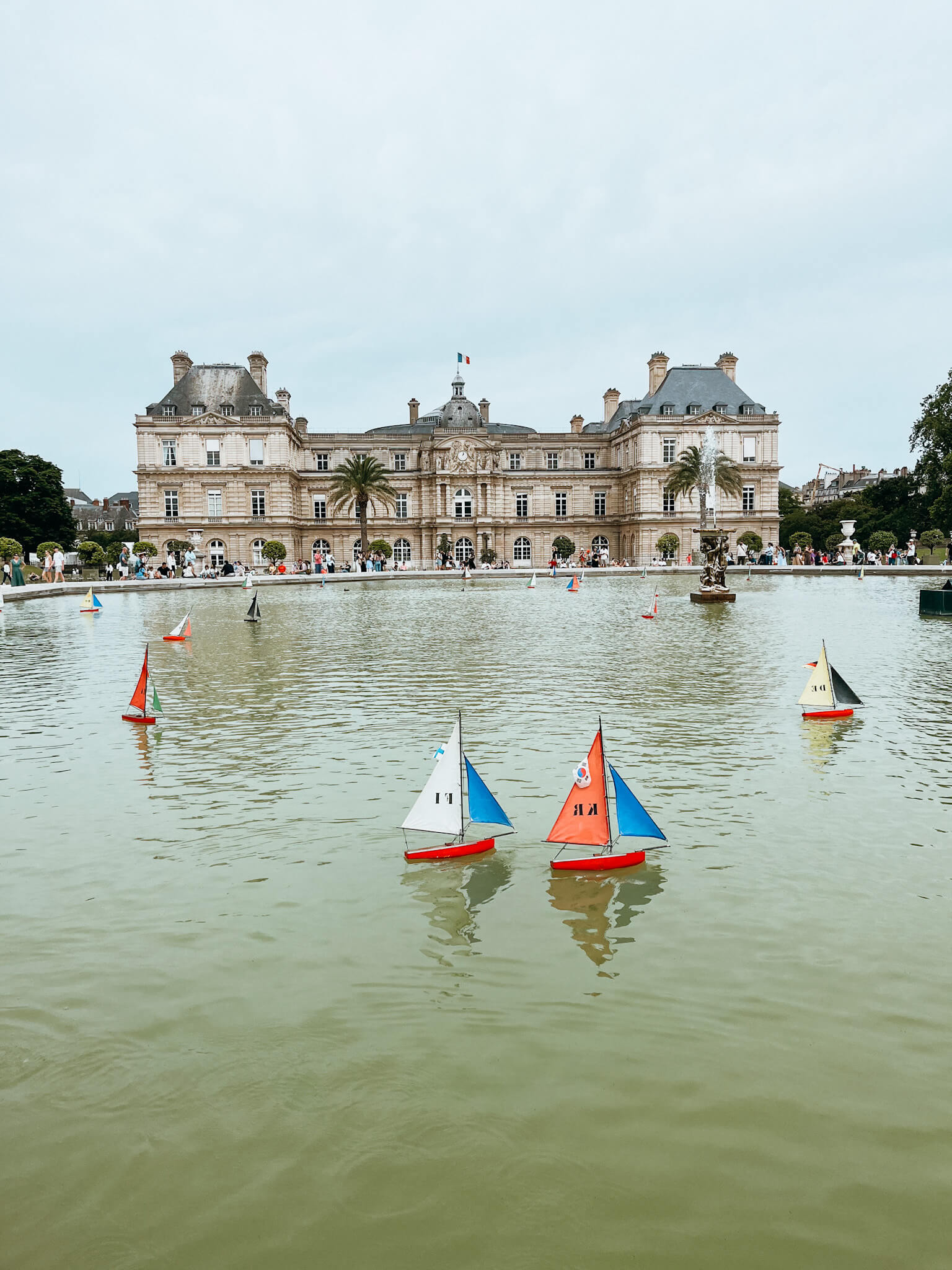 Toy sailboats on large fountain in front of Luxembourg Palace in Paris in May