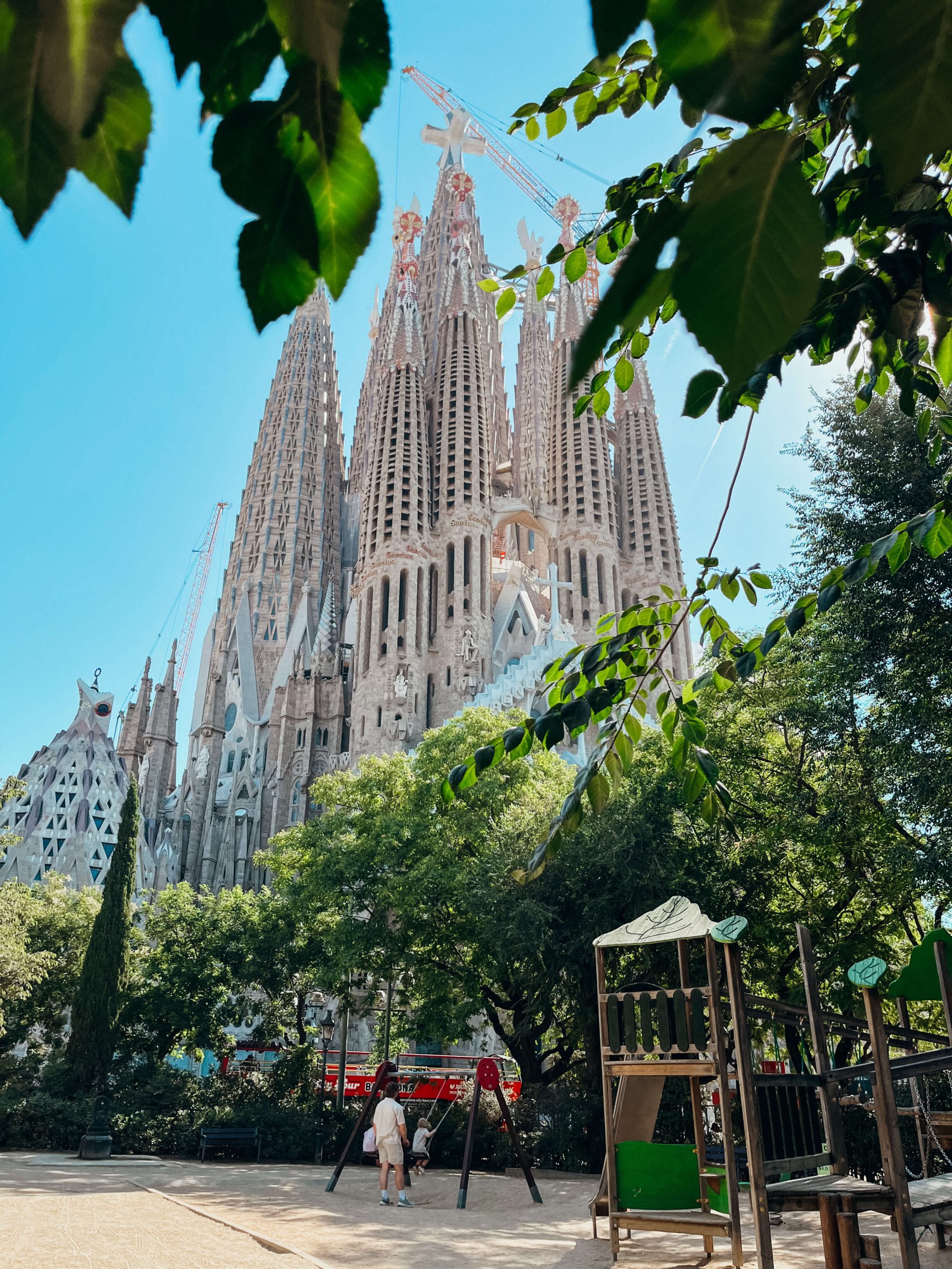 Wooden playground with play structure and swings with Sagrada Familia in the background