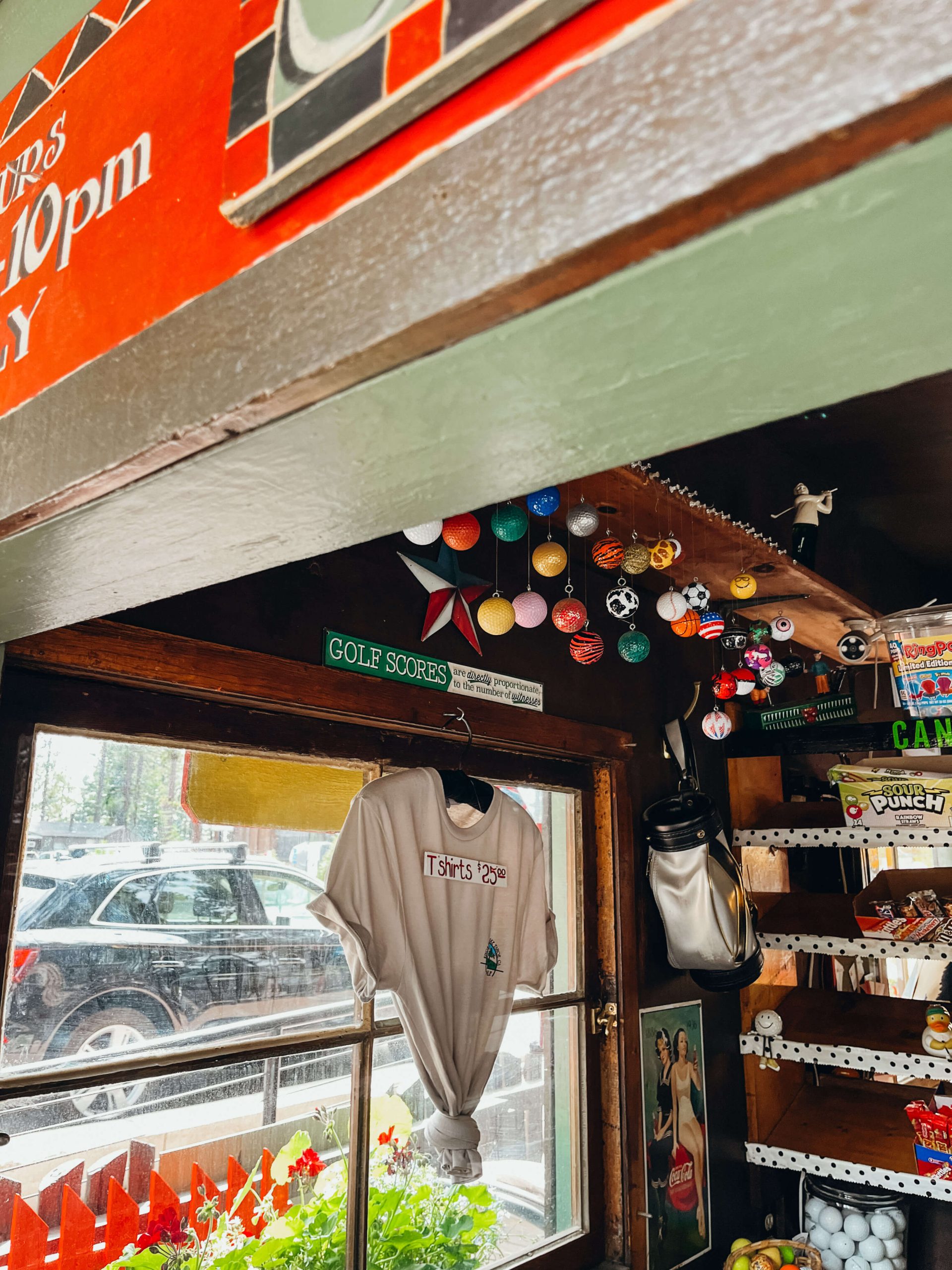 Close up of inside of a small shack selling candy and t-shirts and golf balls hanging from the ceiling at King's Beach Mini Golf