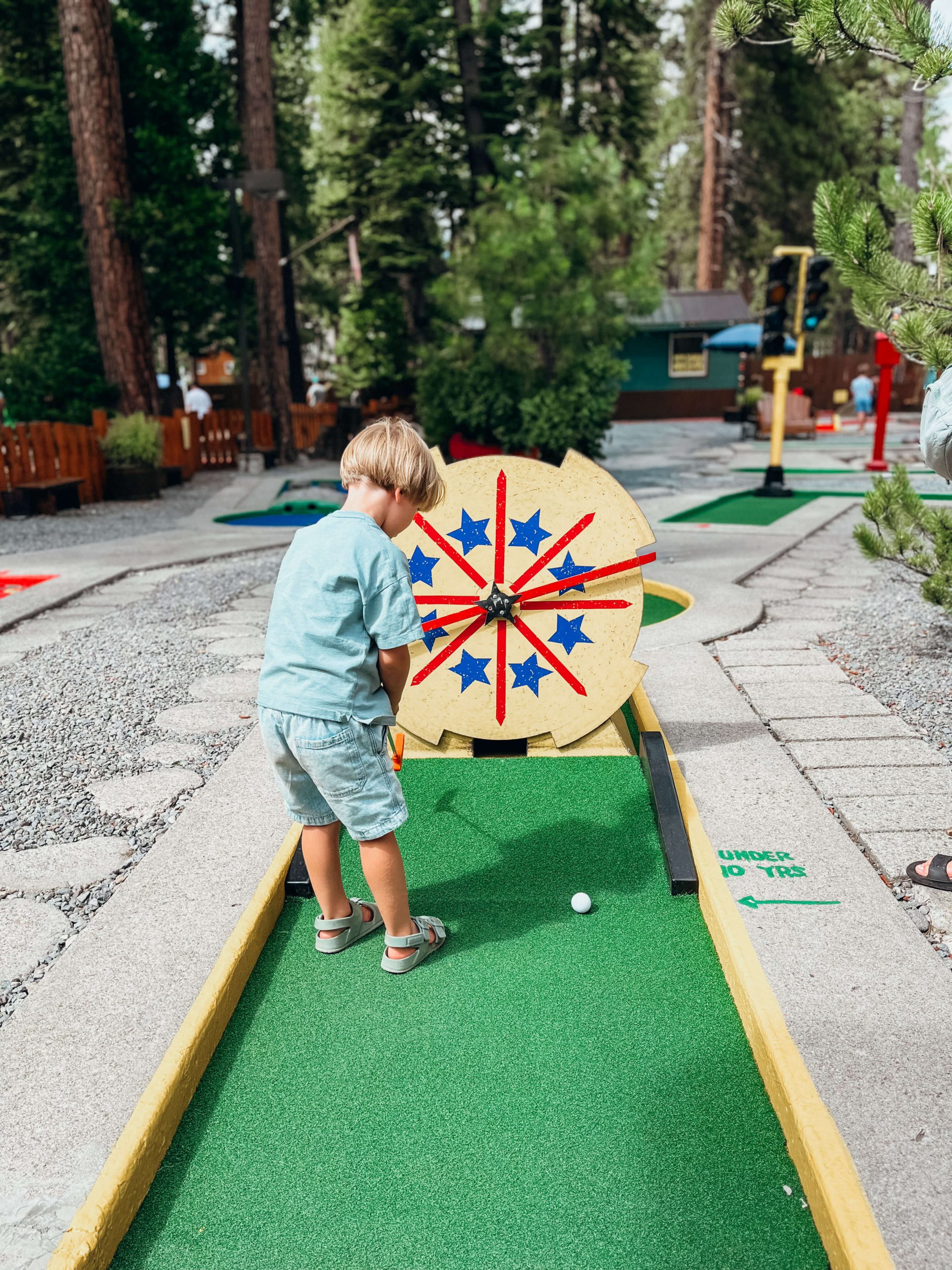 Young boy puts through a moving yellow trap at King's Beach Mini Golf